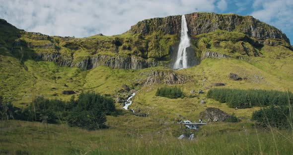 Majestic Scenic Tourist Attraction Bjarnarfoss Waterfall with Its High and Steep Green Cliffs in