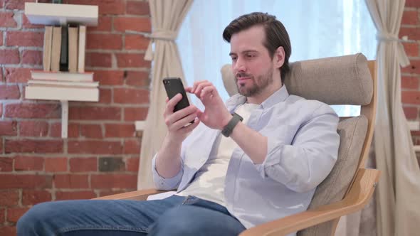 Casual Young Man Having Loss on Smartphone at Home