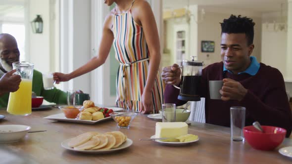 Three generation african american family having breakfast sitting together on dining table at home