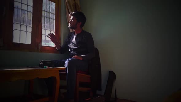 Lone Man Sitting By The Window And Looking Outside On A Sunny Morning