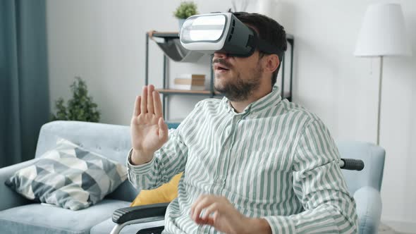 Slow Motion of Handicapped Guy Wearing Vr Glasses Moving Hands Sitting in Wheelchair at Home