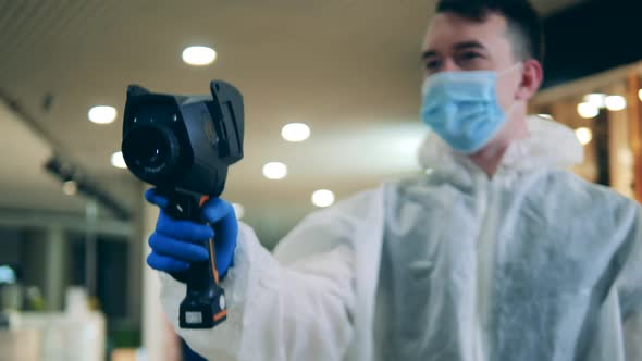 A Man in a Safety Suit Is Using an Infrared Camera for Scanning