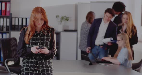 Businesswoman Messaging on Smart Phone in Office