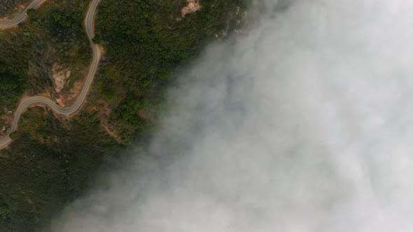 Overhead drone shot of mountain road under the clouds in Malibu Canyon, Calabasas, California, USA