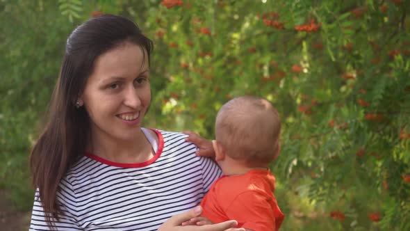 Mom walks in the park with a newborn baby in her arms.