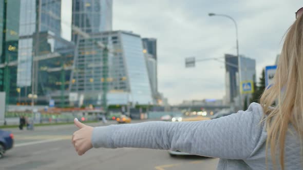 A Girl in the City Center Catches a Taxi or a Passing Car