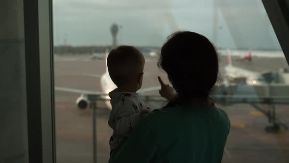 Silhouettes of Mother and Son Looking at Window in Airport