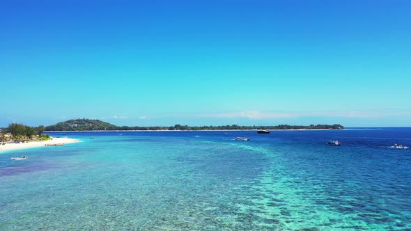 Beautiful healthy coral reef near the coast of tropical island, boats floating in the crystal clear