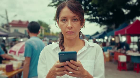 Portrait of a Young Woman Typing on a Smartphone in the Street
