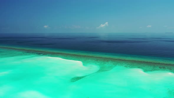 Daytime birds eye abstract shot of a sandy white paradise beach and blue water background in 4K