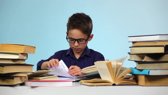 Little Boy Pulls Out Sheets of Books. Blue Background. Slow Motion
