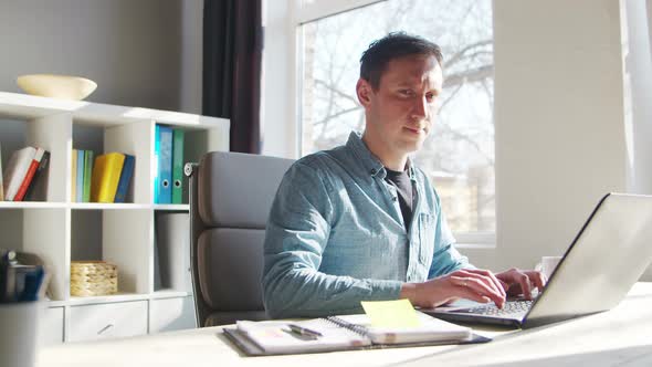 Young male entrepreneur works at home office at the computer.