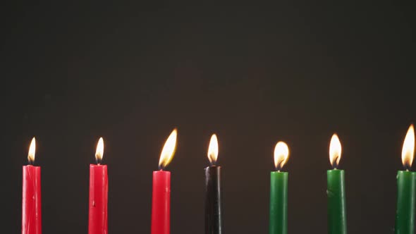 Composition of halloween green, black and red lit candles against black background