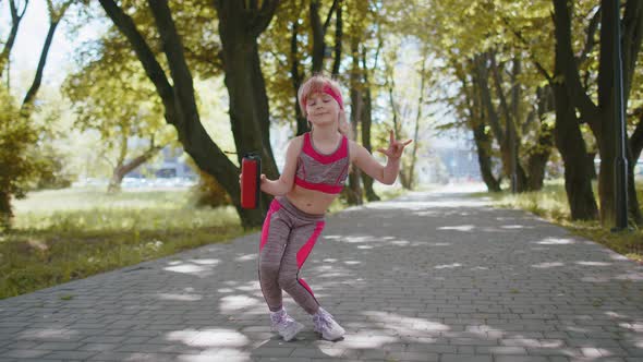 Sport Runner Jogger Child Girl Listen Bluetooth Music Speaker Dancing to Camera Having Fun in Park
