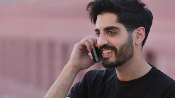 Happy Smiling Bearded Indian Guy Holding Cellphone at Ear Talking with Friend