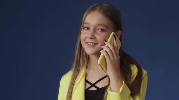 A Teenage Girl in Smart Clothes is Chatting on the Phone with Her Girlfriend