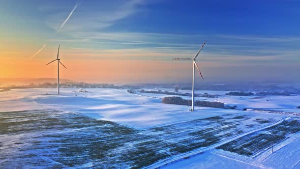 Wind turbine on snowy field at sunrise. Alternative energy.