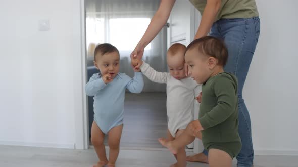 Unrecognizable Woman Leading Toddler Triplets by Hands at Home