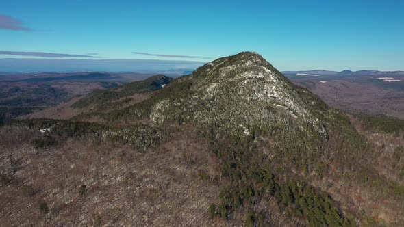 Aerial pull back with decent farther from the snow dusted mountain in Maine