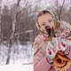 Cute girl in a traditional Russian headscarf and mittens playing on spoons on winter forest backgrou - VideoHive Item for Sale