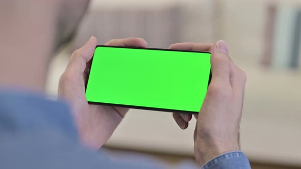 Man Watching Video on Green Mock-up Screen Smartphone