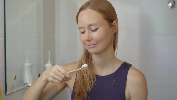 A Young Woman Brushes Her Teeth with a Brush Made of Bamboo Wood. Zero Waste Concept. Biodegradable