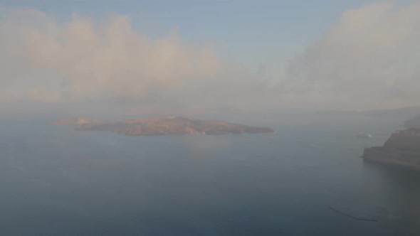 View of the majestic Santorini seascape including the volcano island of Nea Kameni. Foggy conditions