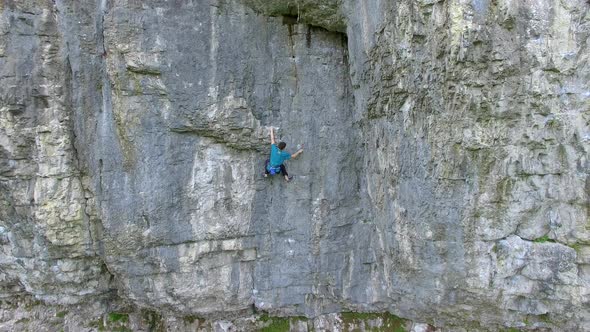 Aerial view of a man rock climbing up a mountain.