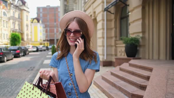 Young Woman with Shopping Bags Walking in a City at Summer Day