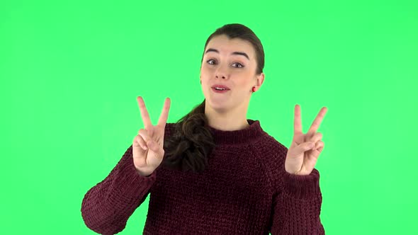 Girl Shows Two Fingers Victory Gestur. Green Screen