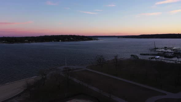 an aerial shot over an empty park looking at the bay during a beautiful sunrise. The sky is pink and