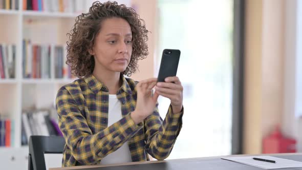 Unhappy Mixed Race Woman with Loss on Smartphone at Work