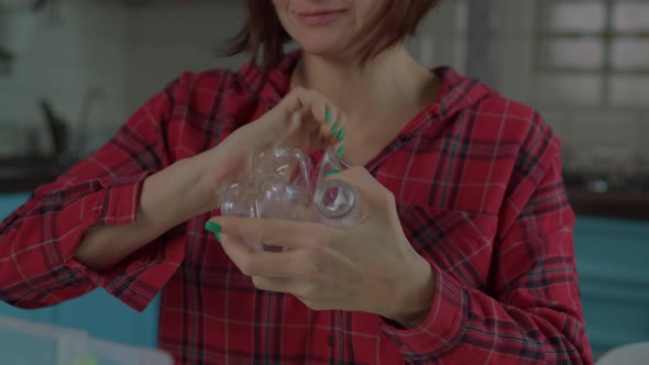 Female Compressing Plastic Bottle While Sorting Recyclable Waste at Home