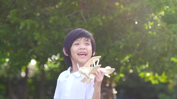 Cute Asian Child Playing Wooden Toy Plane In The Park