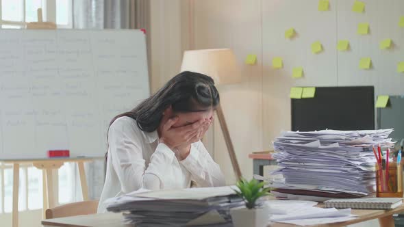 Tired Asian Woman Working Hard With Documents At The Office