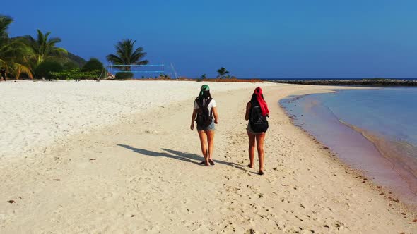 Female models happy together on marine lagoon beach trip by aqua blue water with bright sandy backgr