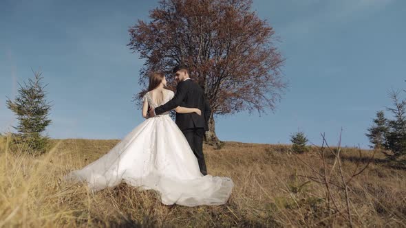 Newlyweds. Caucasian Groom with Bride Near Beautiful Autumn Tree. Wedding Couple