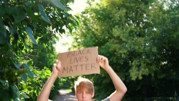 Young Teenager Male of Caucasian Ethnicity in Blue Shirt Holds Cardboard Box with Handwritten Text