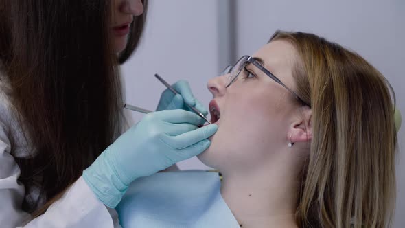 Female Dentist in Medical Gloves Scaling with Tools Patient's Teeth in Clinic