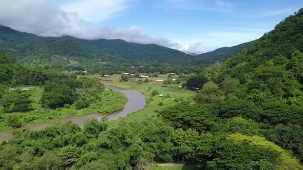 Windy River flowing through Valley surrounded by Lush Green Mountains in Northern Thailand