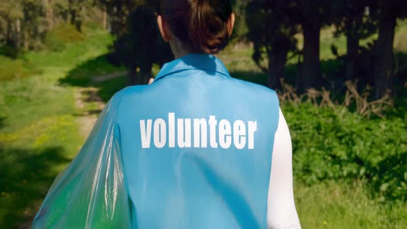 Volunteer Woman Cleans Up Plastic Bottles and Garbage in the Forest and Turns Around