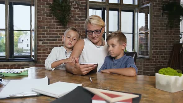 Woman in Glasses Making Exercises with Two Pupils on Tablet Happy Little Boys 