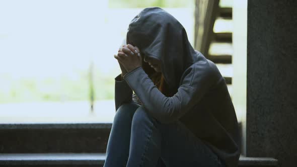 Depressed Young Female in Hoodie Sitting Alone on Stairs Thinking About Problems