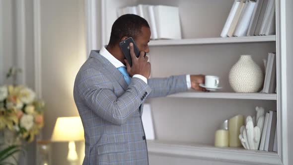 Adult Rich Man Is Talking By Cell Phone in Hall of His Luxury House, Black Man Dressed Suit