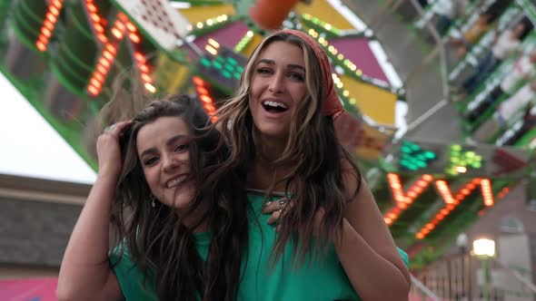 Young woman jumps on others back as they laugh and smile