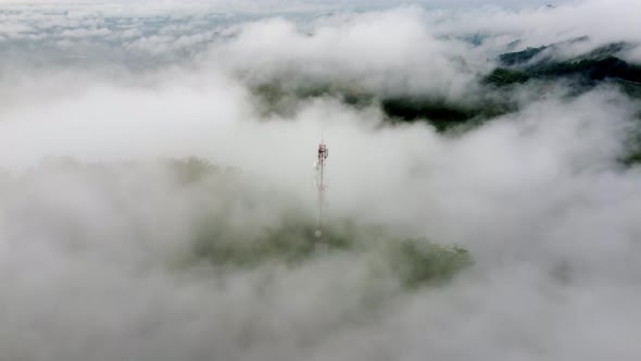 Aerial fly forward fast motion morning low cloud at telco tower
