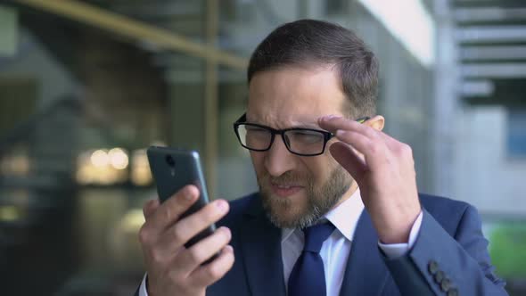 Manager in Eyeglasses Trying Read Smartphone Message, Poor Eyesight, Health Care