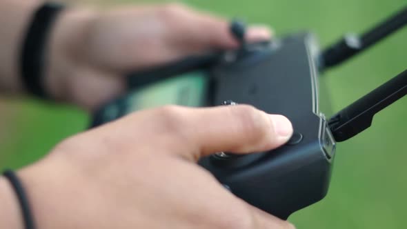 Hands turning on drone remote controller outdoors, close up