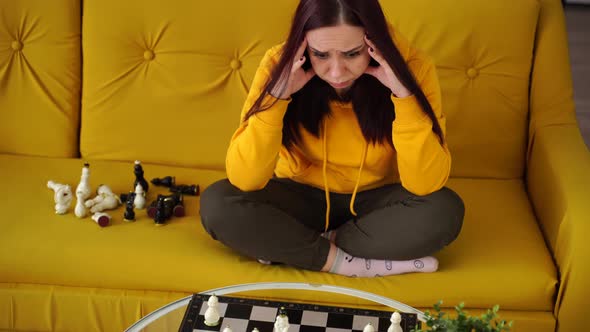 Young Upset Woman Playing Chess Sitting on Sofa