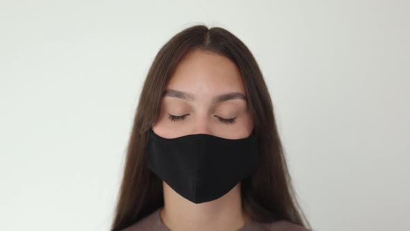 Portrait of Pretty Young Brunette Female Put Off Black Protective Medical Mask